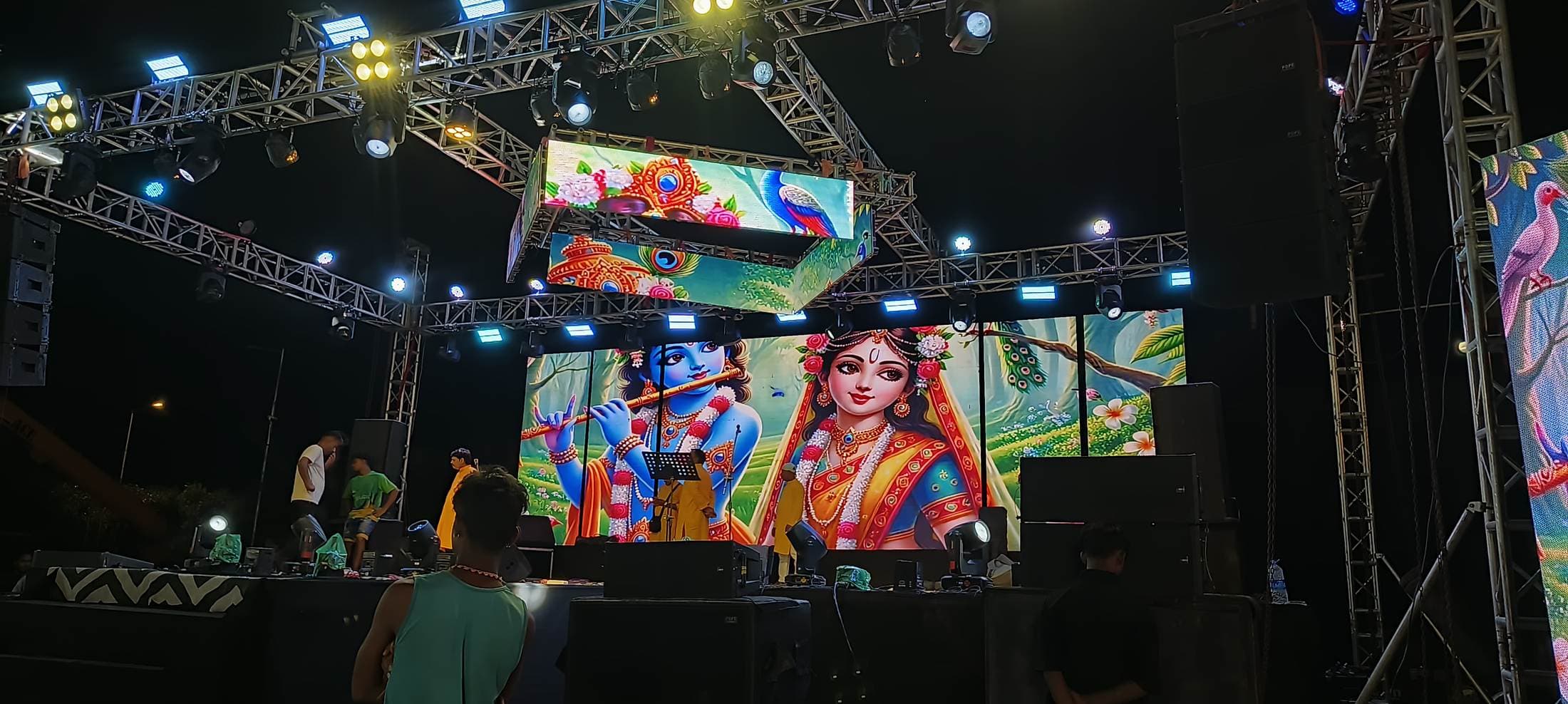 Full outdoor LED stage build at night seen from the audience, with truss roof and stage lighting.